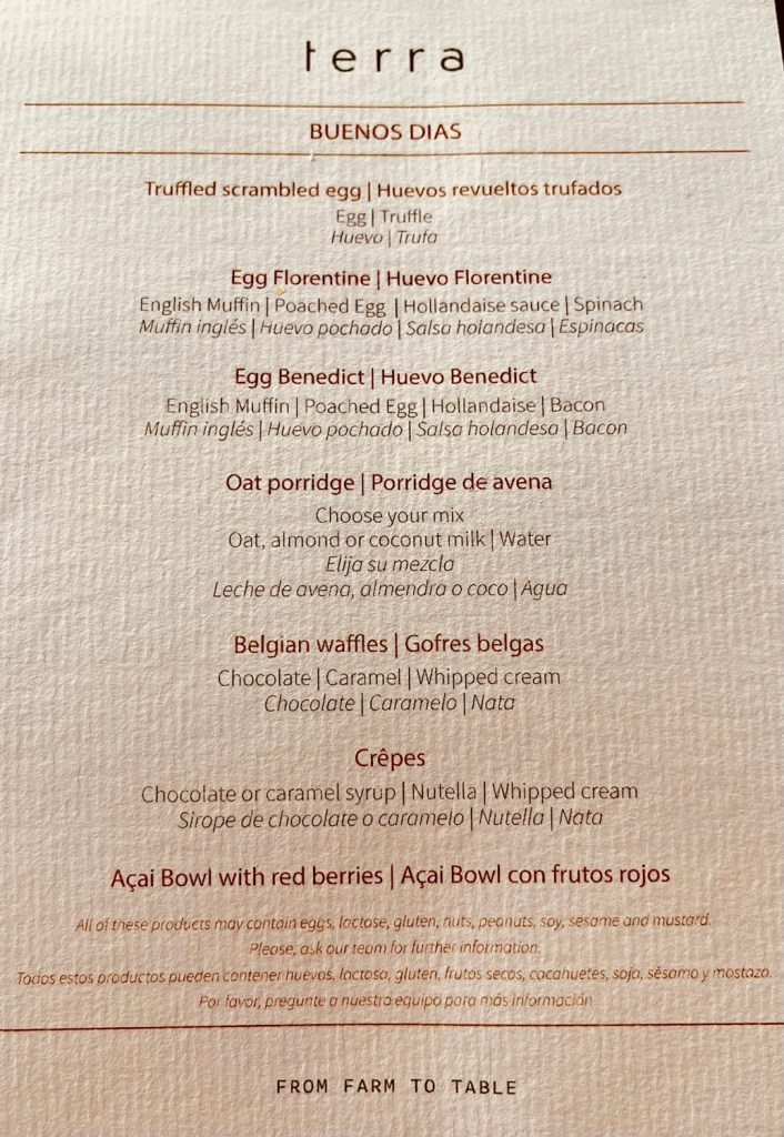 Breakfast menu featuring truffled scrambled egg, egg Florentine, egg Benedict, oat porridge, Belgian waffles, crêpes, and an acai bowl with red berries; includes descriptions in both English and Spanish.