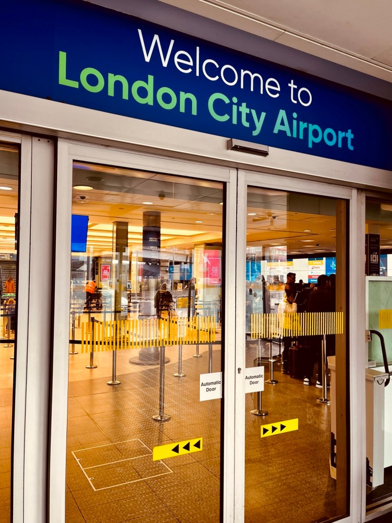 Entrance to London City Airport with a welcome sign and visible security checks.