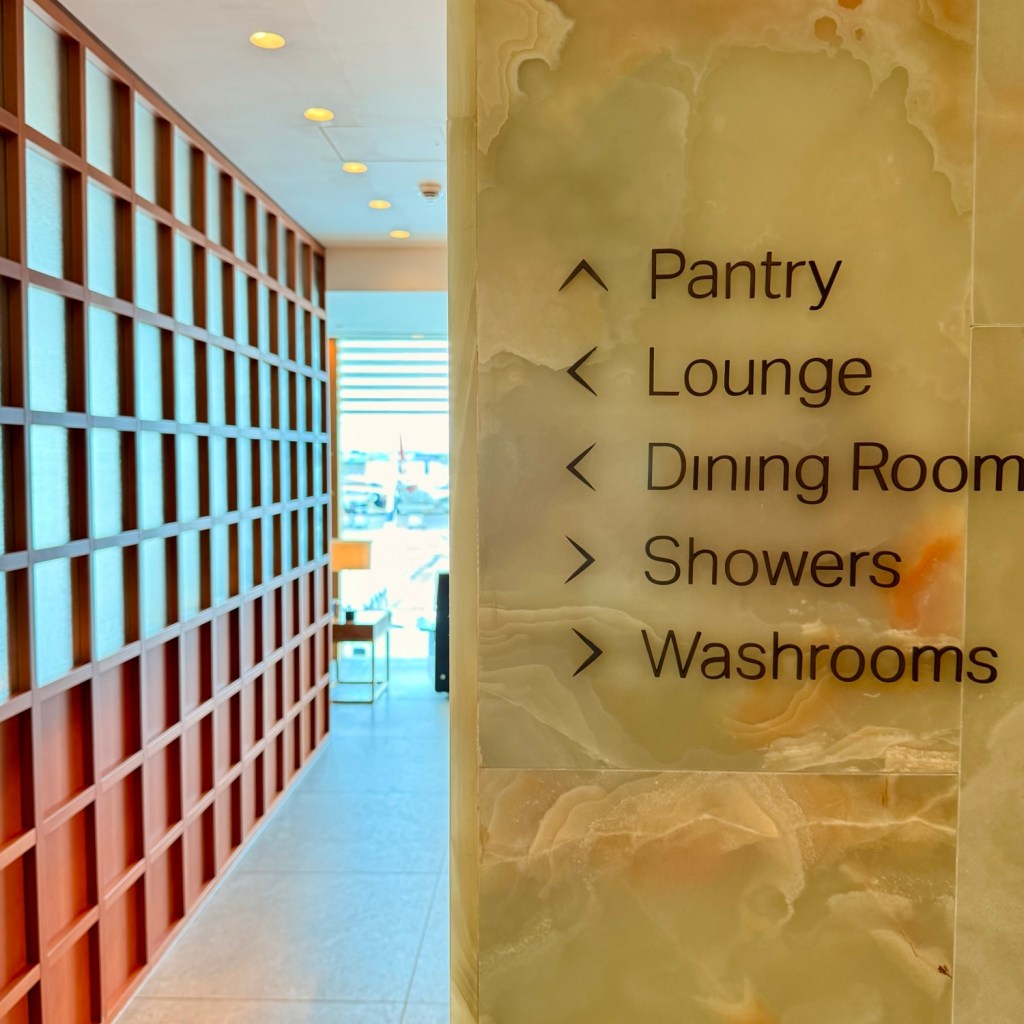 Signage inside the lounge at an airport terminal, indicating directions to the pantry, lounge, dining room, showers, and washrooms.