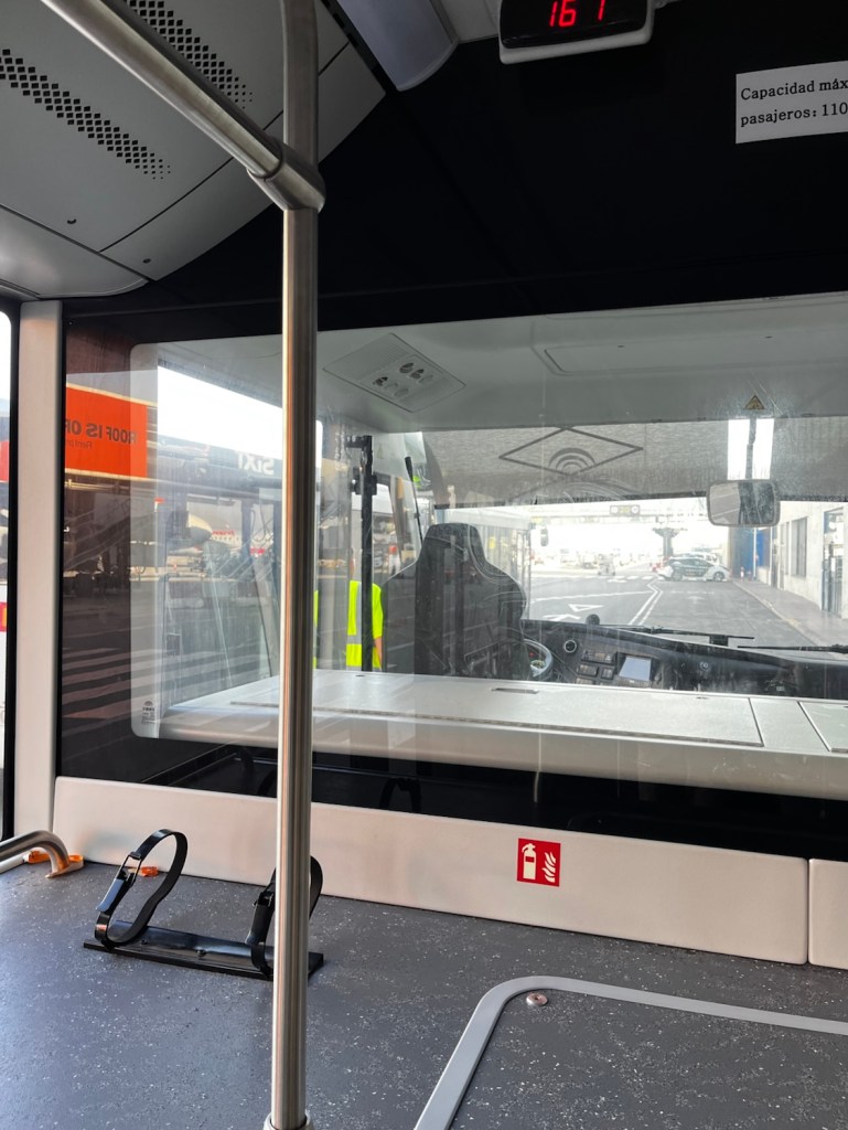 Interior view of a transport vehicle showing the driver's area and seating arrangement, with a display indicating capacity and safety information.