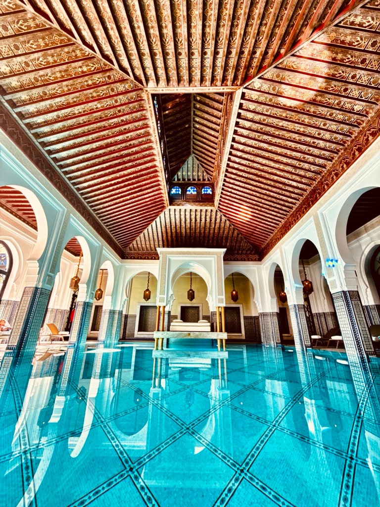 Interior of the La Mamounia Spa featuring intricate wooden ceiling and turquoise tiled floor with reflections.