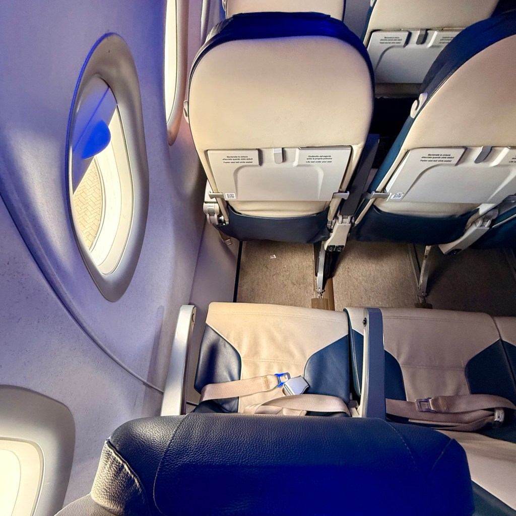 Interior view of an airplane cabin featuring several empty seats and a large window, showcasing the design and layout typical of business class.