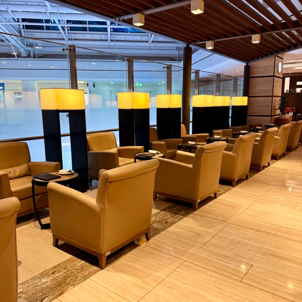 Interior view of a lounge featuring tan leather chairs, small tables, and ambient lighting.
