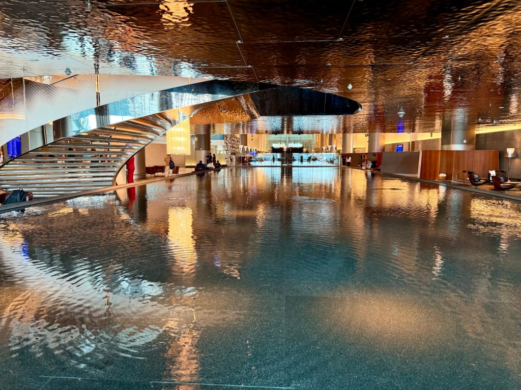 Interior view of the Al Mourjan Business Lounge featuring a large reflection pool and modern design elements.