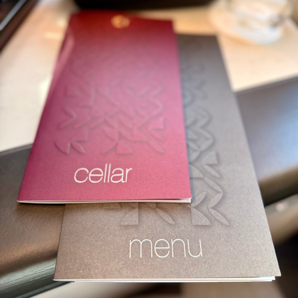 Close-up of Qatar Airways menu and wine cellar brochure on a dining table, highlighting luxury travel experience.