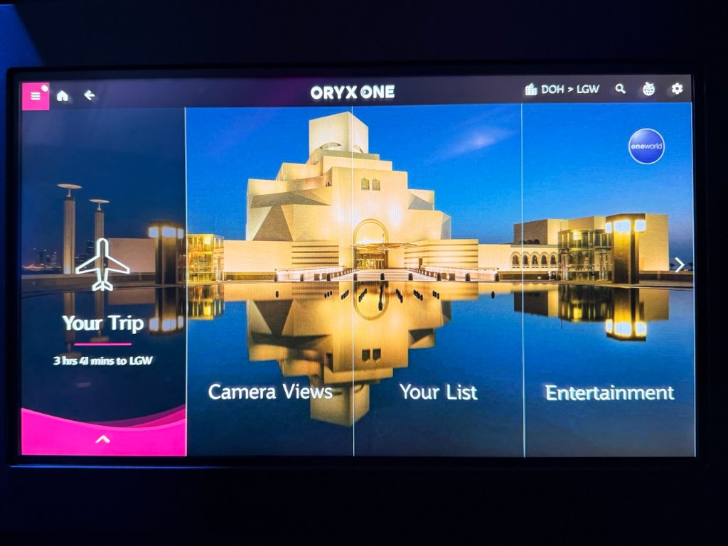 In-flight entertainment screen displaying Qatar Airways' Oryx One system with options for trip details, camera views, and entertainment.