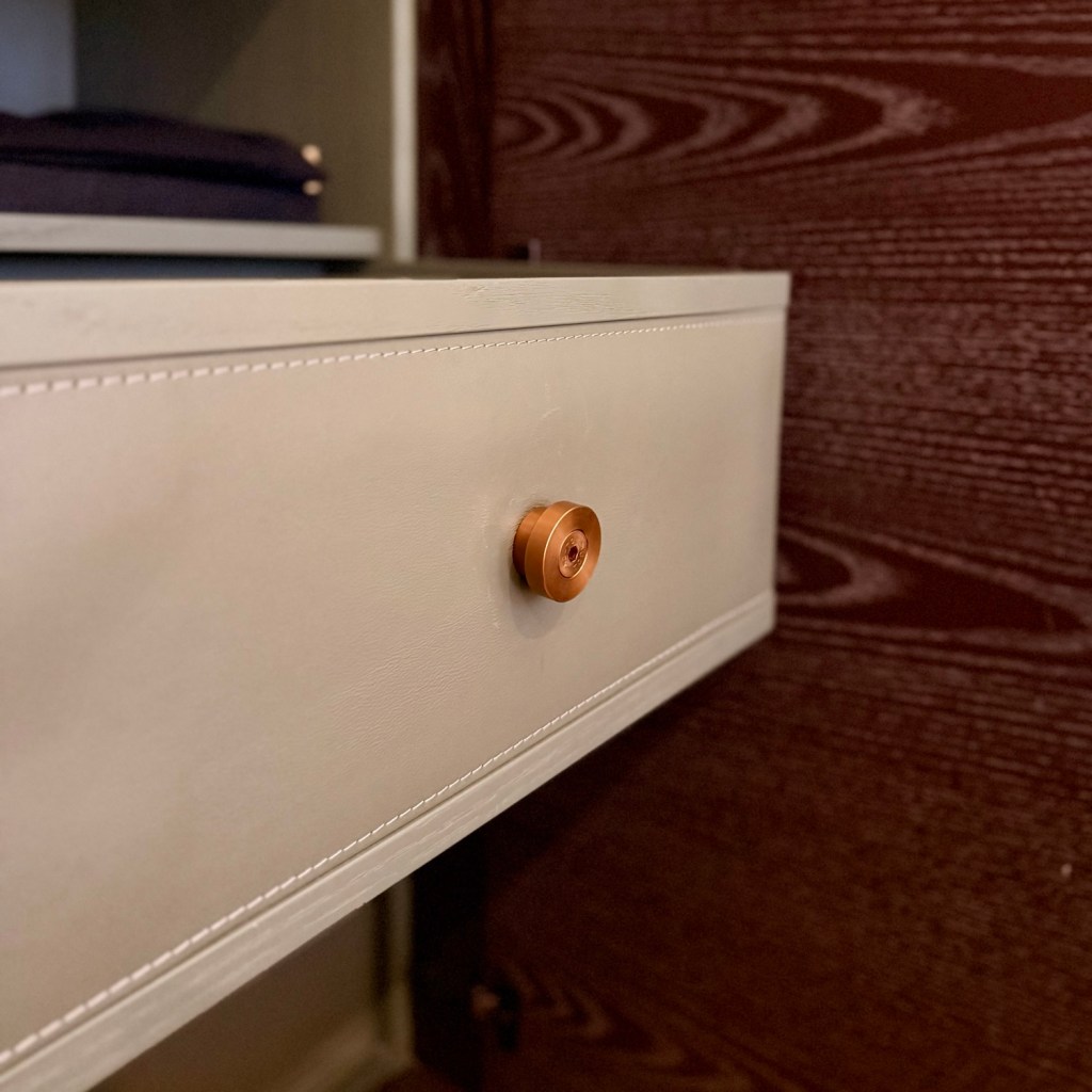 Close-up of a stylish drawer featuring a round wooden knob, positioned against a textured wooden background, highlighting luxury design details.